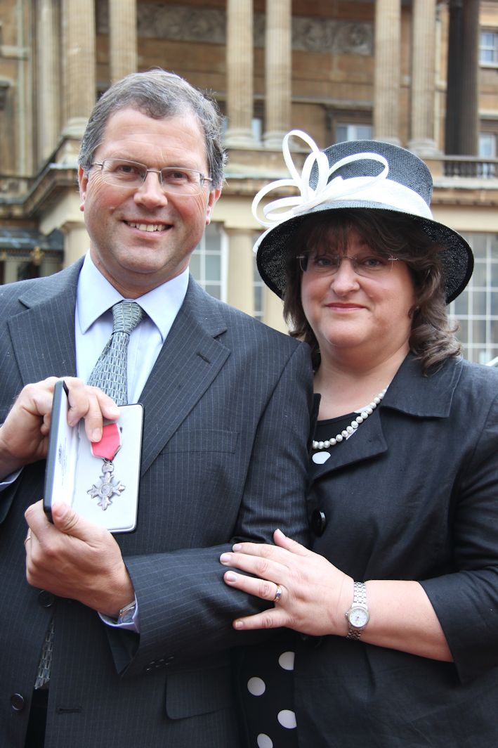 Robert and Helen Mitchell pose proudly outside Buckingham Palace after receiving his MBE.